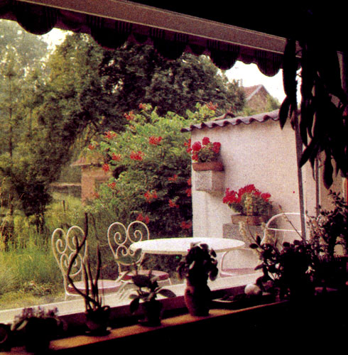 Пример использования сада как продолжения жилой зоны: огромная терраса становится частью жилого помещения. Из окна виден на фоне высоких деревьев участок, ограниченный стеной 